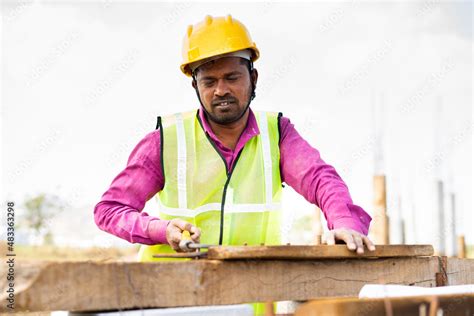 Indian Construction Worker With Hard Hat Bending Steel Rod At Workplace