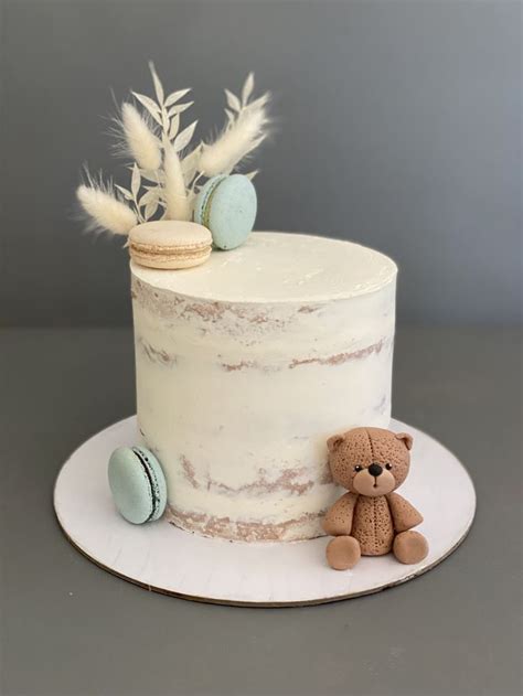 A White Cake With Frosting And A Teddy Bear On The Side Sitting Next To It