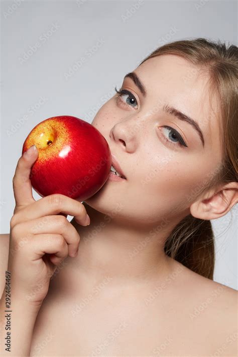 Close Up Portrait Of A Blond Girl With Naked Shoulders She Bites A Red Apple Girl Has Nude