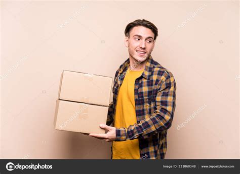 Young Caucasian Man Holding Boxes Looks Aside Smiling Cheerful Pleasant