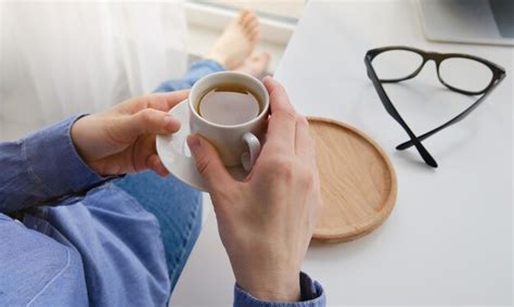 Manos femeninas sosteniendo una taza caliente de café o té Foto Premium