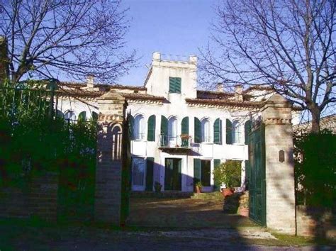 A Large White Building With Green Shutters On The Front And Side Doors