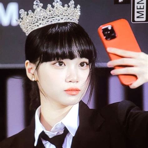 A Woman Wearing A Tiara Taking A Selfie With Her Cell Phone In Front Of Her