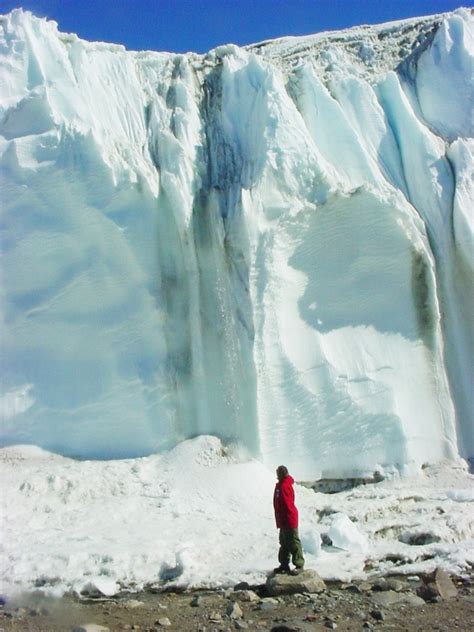 An MCM scientist (foreground) is dwarfed by a waterfall coming off the ...