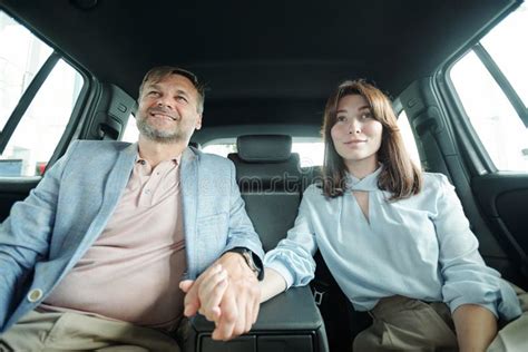 Affectionate Happy Middle Aged Husband And Wife Sitting On Backseat Of