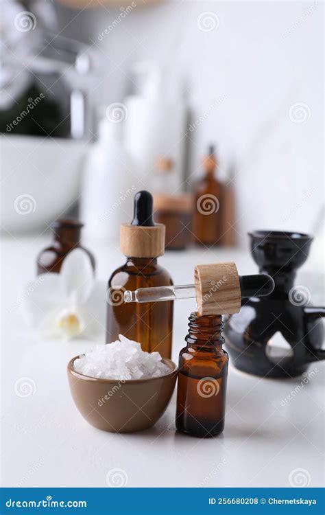 Essential Oils And Sea Salt On White Table In Bathroom Stock Photo