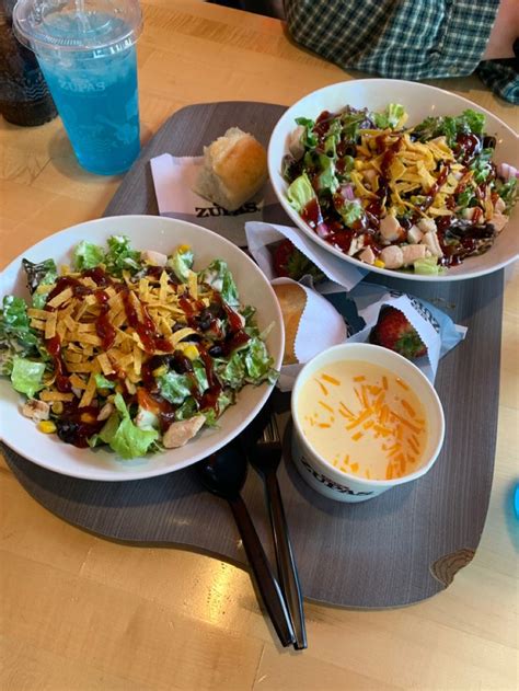 two white bowls filled with salad sitting on top of a wooden table next ...