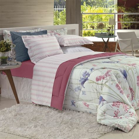 A Bed With Pink And Blue Comforters In A Room Next To A Table On A