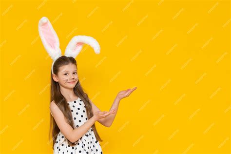 Premium Photo A Beautiful Girl In An Easter Bunny Costume Points At The Advertisement And Smiles