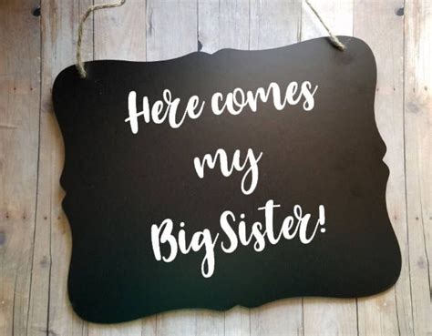 A Sign That Says Here Comes My Big Sister Hanging On A Wooden Wall With