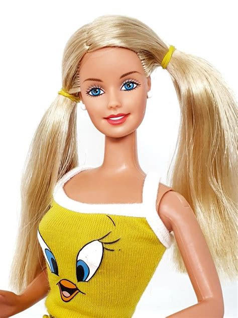 A Barbie Doll With Blonde Hair And Blue Eyes Wearing A Yellow Sweater