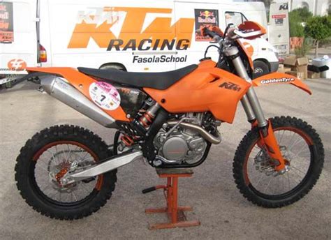 An Orange Dirt Bike Sitting On Top Of A Stand In Front Of A White Truck