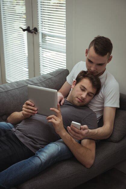Casal Gay Usando Tablet Digital E Celular Enquanto Estava Deitado No Sof Foto Gr Tis