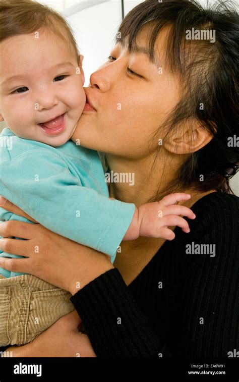 young Korean mother kissing mixed race (asian / caucasian) baby girl ...