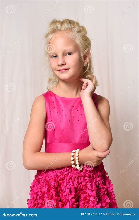 Petite Fille Blonde Dans La Pose De Sourire De Robe Rose Dans La Perspective Du Mur Image Stock