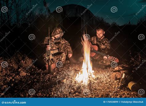 Two Military Men With Guns Sitting By Fire Stock Image Image Of