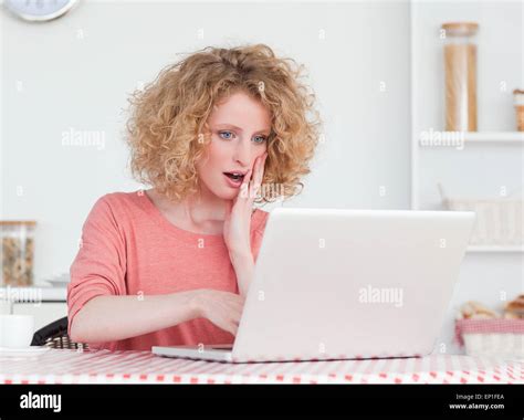 Good Looking Blonde Female Relaxing With Her Laptop While Sitting In The Kitchen Stock Photo Alamy