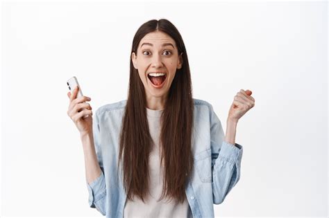 Free Photo Excited Brunette Girl Screams Amazed Holding Smartphone