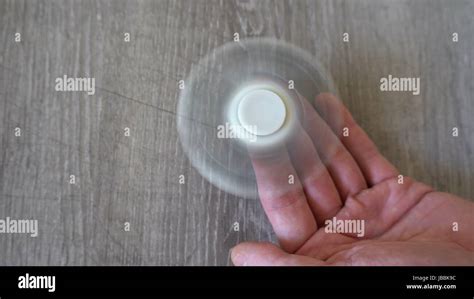 White Hand Spinner Or Fidgeting Spinner Rotating On Mans Hand Stock