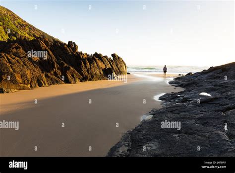 A Person Stands Alone On A Remote Beach In Australia And Watches The