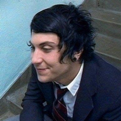 A Man With Black Hair Wearing A Suit And Tie Sitting On The Ground Next