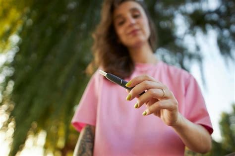 Close up da mão de uma mulher segurando um cigarro eletrônico sistema