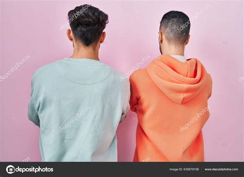 Joven Pareja Gay Hispana Pie Sobre Fondo Rosa Pie Mirando fotografía de stock Krakenimages