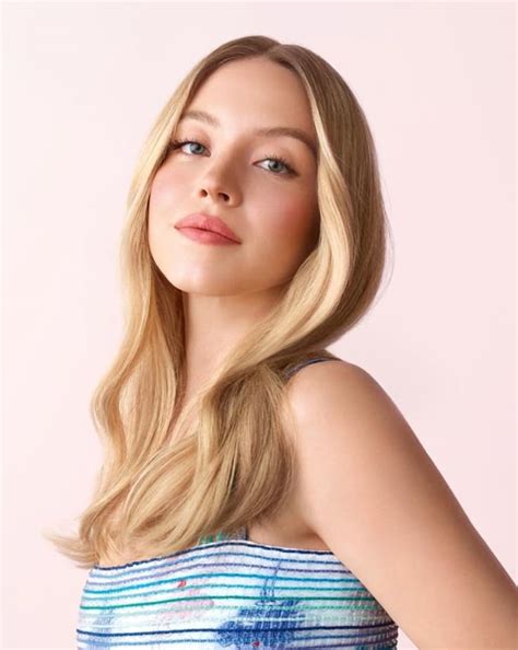 A Woman With Long Blonde Hair Wearing A Blue And White Striped Top Posing For The Camera