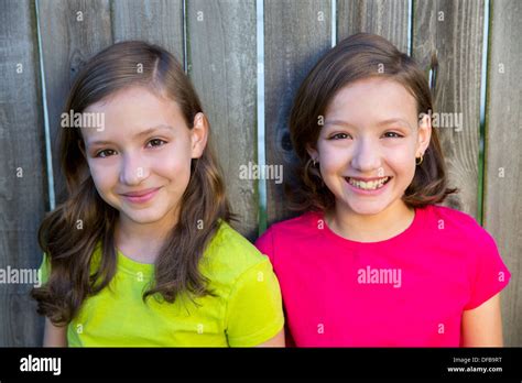 Happy twin sisters with different hairstyle smiling on wood backyard fence Stock Photo - Alamy