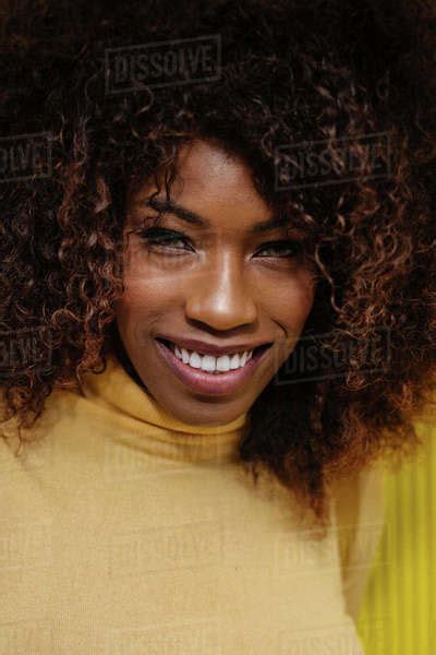 Portrait Of A Curly Haired Black Woman Looking At Camera In Front Of A