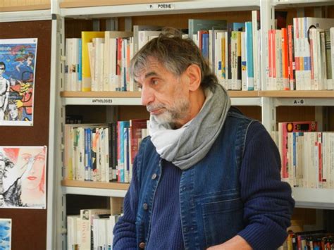 An Older Man Standing In Front Of A Bookshelf With Many Books On It