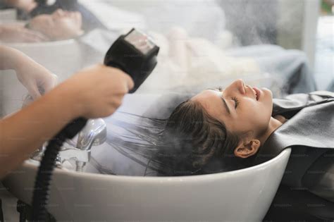 Professional hairdresser working to water washing hair clean with woman ...