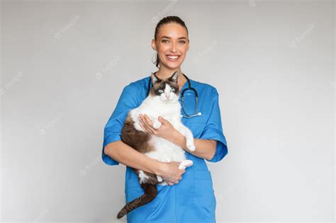 Premium Photo | Happy veterinarian lady in uniform holding feline pet gray background