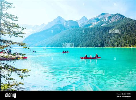 Mid Day Photograph Of Lake Louise In Alberta With Tourists In Canoes