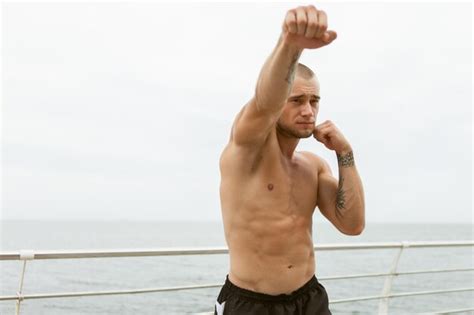 Premium Photo Muscular Male Fighter With A Naked Torso Doing Hand Punches On The Beach