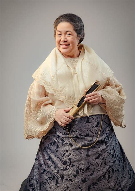 An Old Woman In A Dress And Shawl Holding A Book Smiling At The Camera