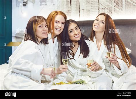 Young Women In White Bathrobe With Champagne Glasses At A Spa Party In