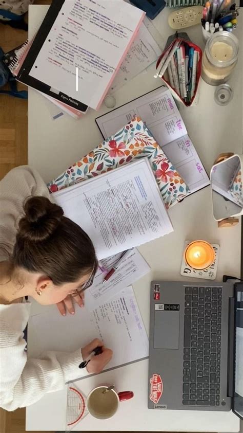 A Woman Sitting At A Desk With Papers And Laptop Computer On Top Of It