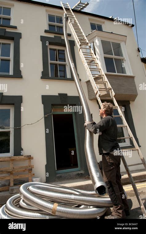 A Man Installing Flexible Metal Chimney Flue Liner To A House For A