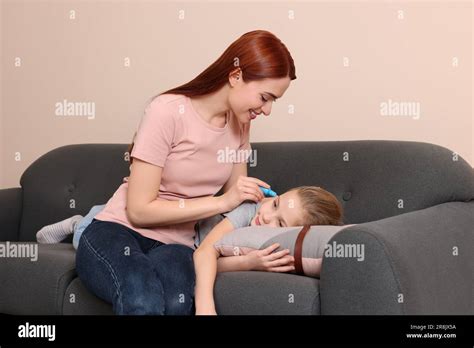 Mother Dripping Medication Into Daughters Ear In Living Room Stock