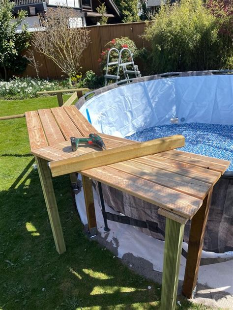 An Above Ground Swimming Pool With A Wooden Table In The Foreground And