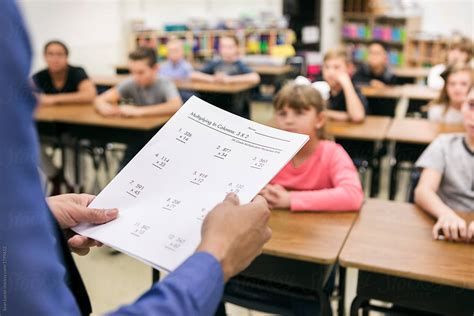 Classroom Teacher Holding Math Test In Front Of Class By Stocksy