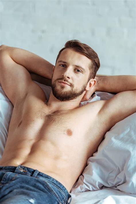 Good Looking And Muscular Man Lying On Bed And Looking At Camera In