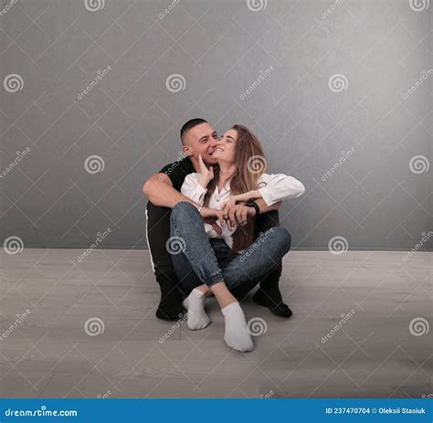 The Guy Hugs The Girl From Behind And Kisses Sitting On The Floor