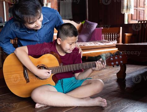 familia asiática guapo feliz padre e hijo tocando la guitarra juntos