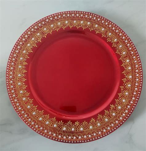 A Red And Gold Plate With Pearls On The Rim Is Sitting On A Marble Surface