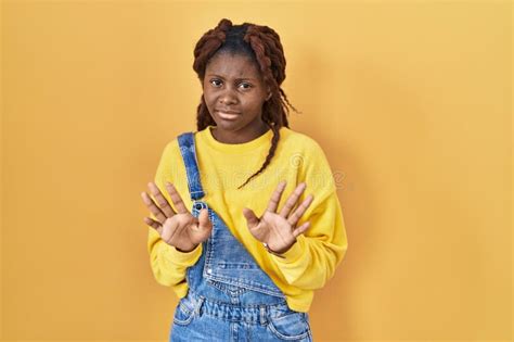 African Woman Standing Over Yellow Background Checking The Time On