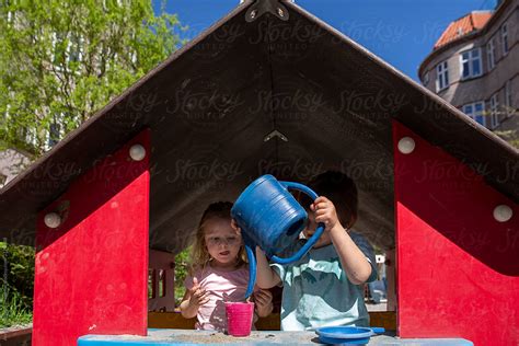 Siblings Playing Outside With A Watering Can By Stocksy Contributor