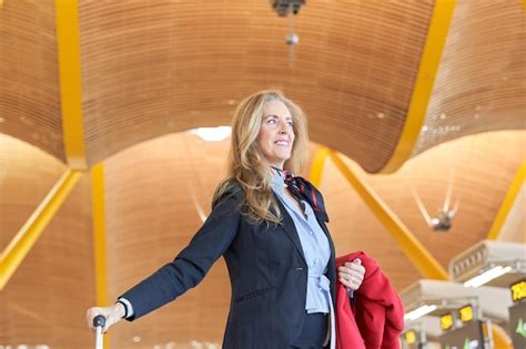 Premium Photo Elegant Mature Flight Attendant With A Suitcase At The Station