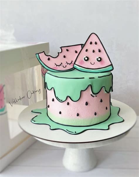 A Pink And Green Cake Sitting On Top Of A White Plate Next To A Box